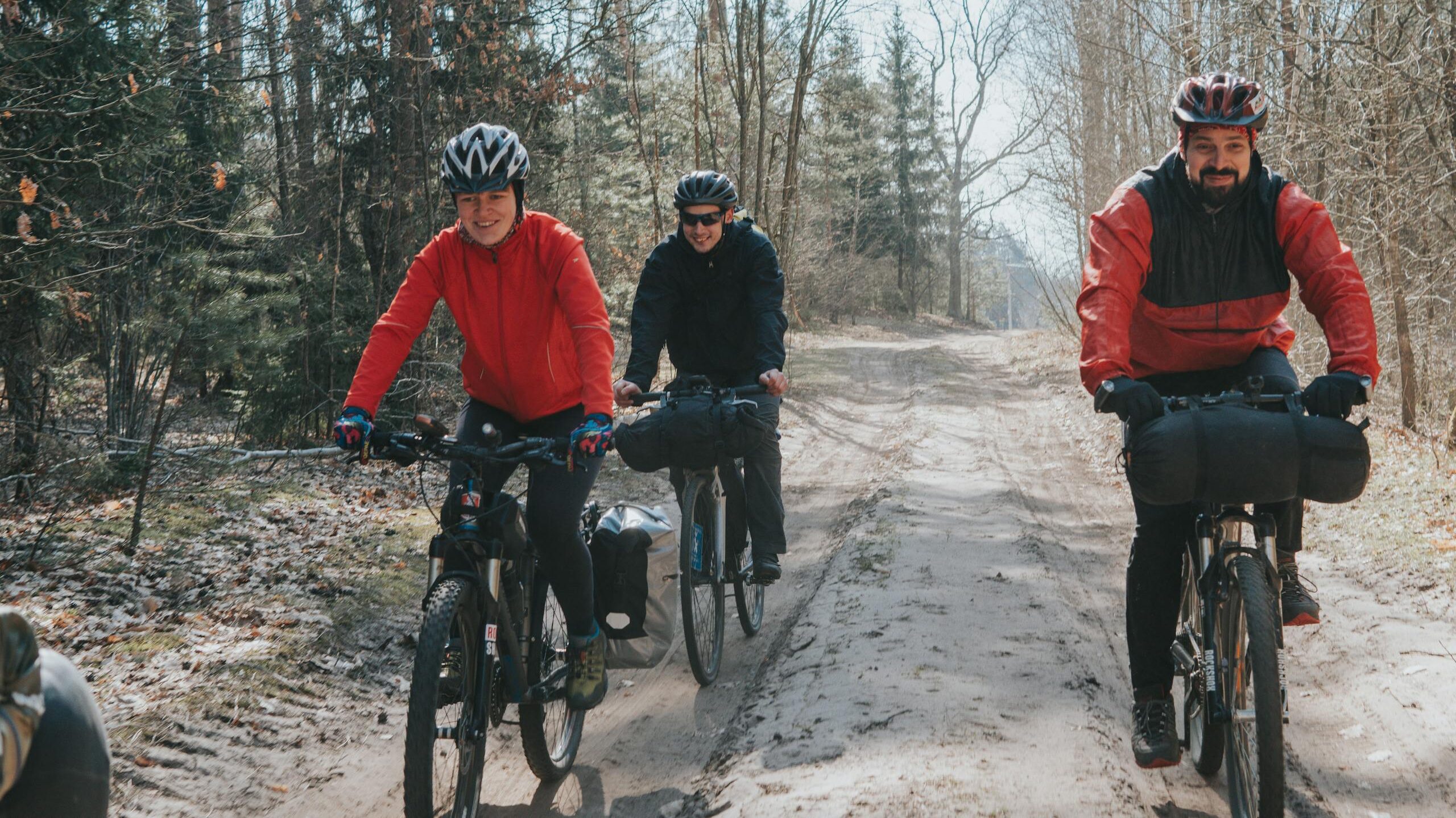 Three bikers ride through a forest path, enjoying outdoor adventure in Belarus.